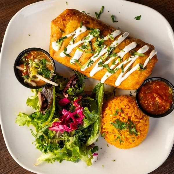 Golden-fried chimichanga drizzled with crema, served with rice, salad, and two dipping sauces.