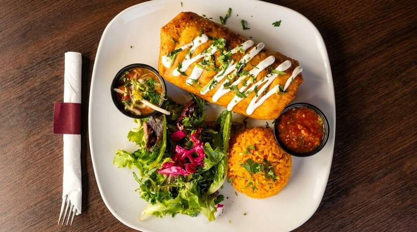 Golden-fried chimichanga drizzled with crema, served with rice, salad, and two dipping sauces.